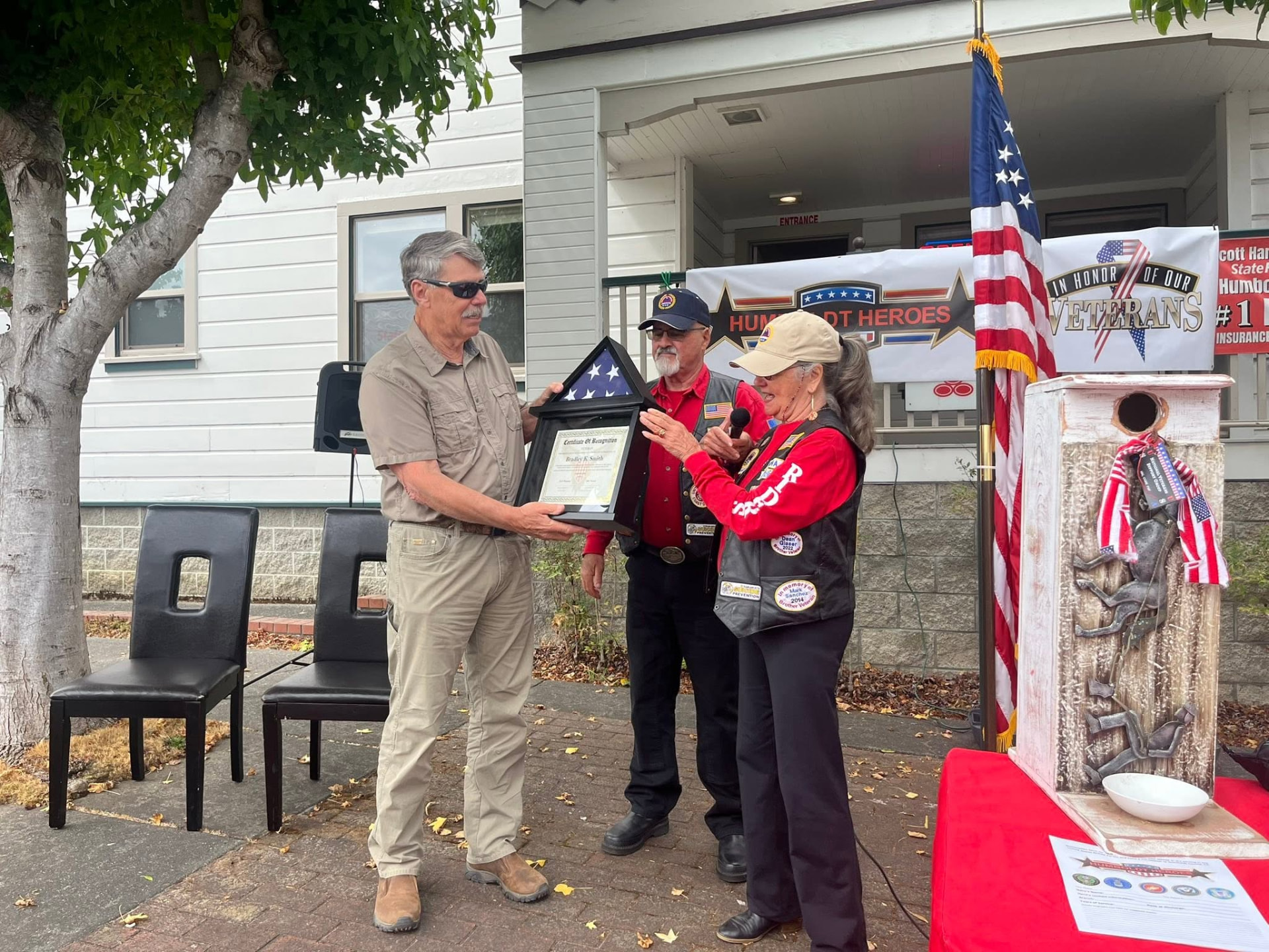A Humboldt Heroes honoree receiving a framed flag and certificate during an outdoor ceremony
